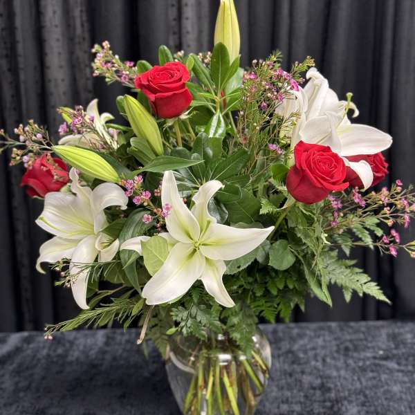 Bouquet of red roses and white lilies in a clear glass vase