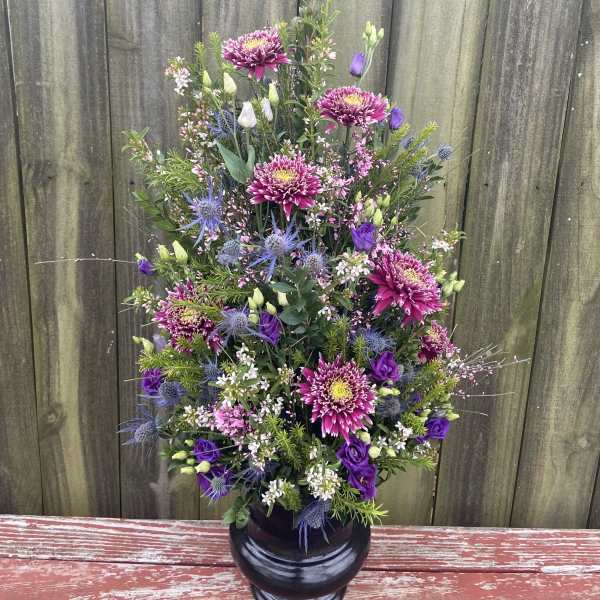 Tall bouquet of purple and pink flowers in a black vase