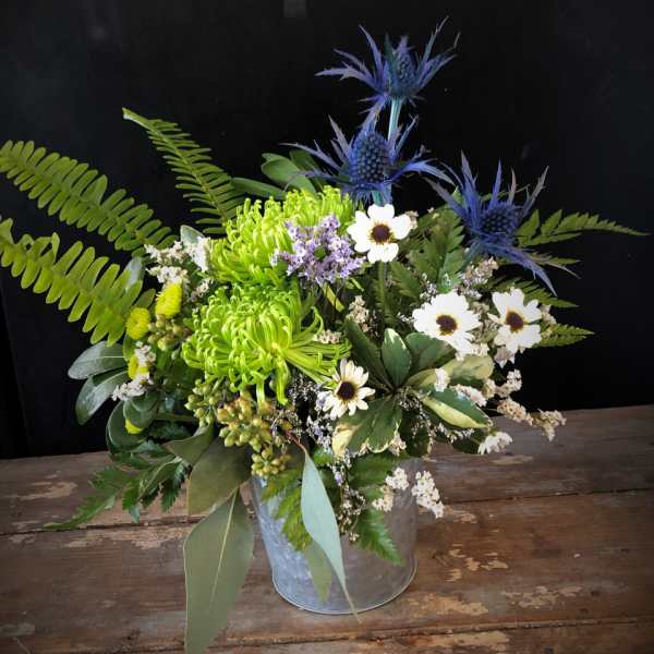 Mixed bouquet with green chrysanthemums, white daisies, and blue thistle in a metal bucket