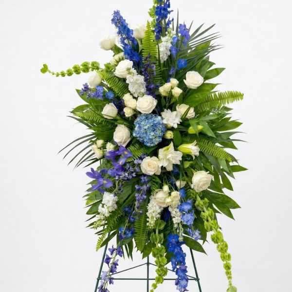 Tall standing floral spray with white and blue flowers on a metal easel