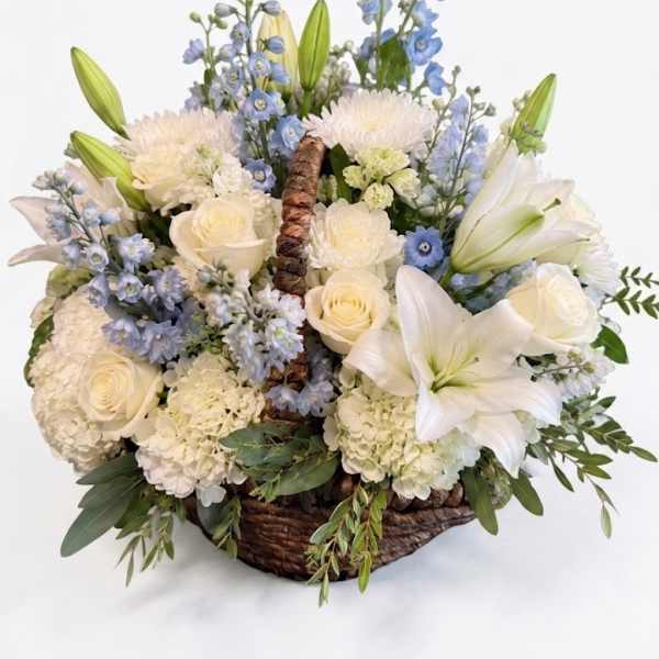 Basket arrangement of white lilies, roses, and blue flowers