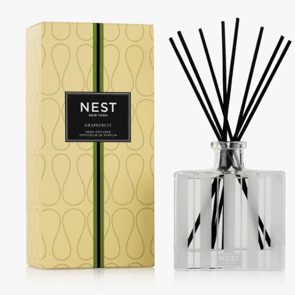 Reed diffuser in a clear glass bottle with black reeds and a yellow box