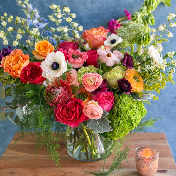 Mixed bouquet of colorful flowers in a glass vase on a table