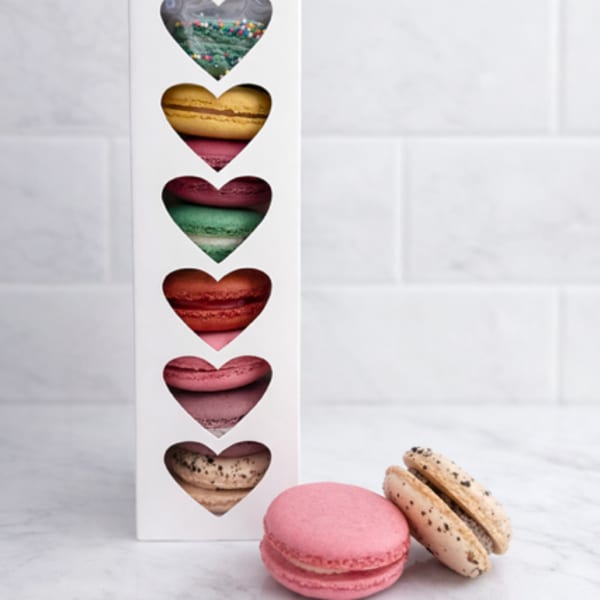 Box of assorted heart-shaped macarons with two macarons in front