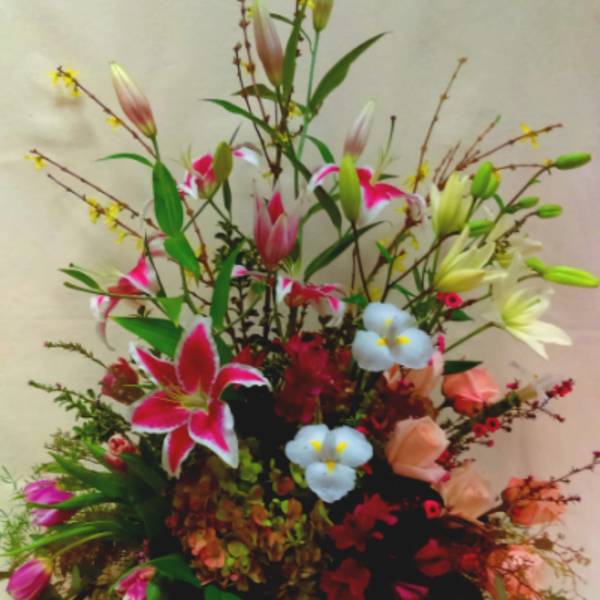 Mixed flower arrangement in a wicker basket with lilies and roses
