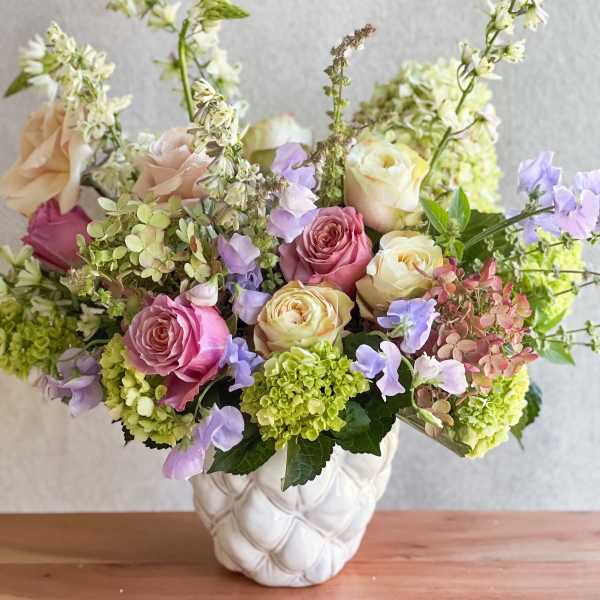 Mixed pink and cream roses in a white vase with lavender flowers