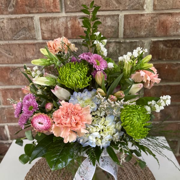 Mixed bouquet in a glass vase with pink, purple, blue, and green blooms