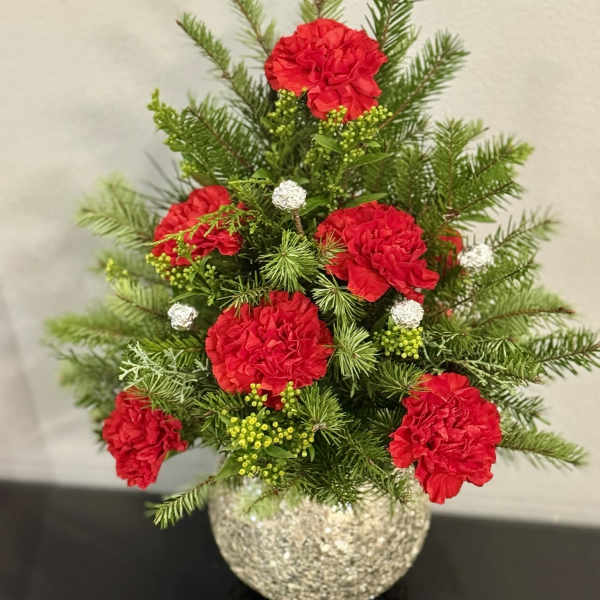 Red carnations in a glittery round vase with evergreen sprigs