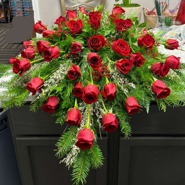Cascade of red roses with evergreen accents on a dark table