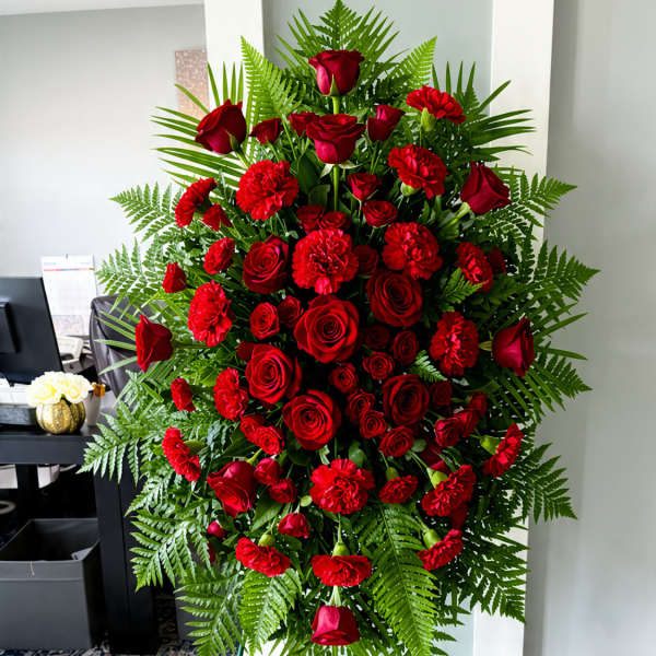 Standing spray of red roses and carnations with fern greenery