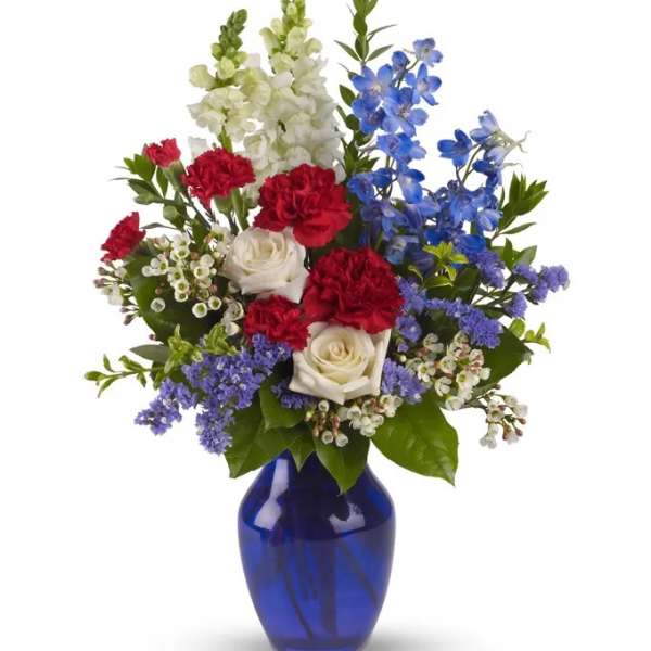Mixed bouquet of red, white, and blue flowers in a blue vase