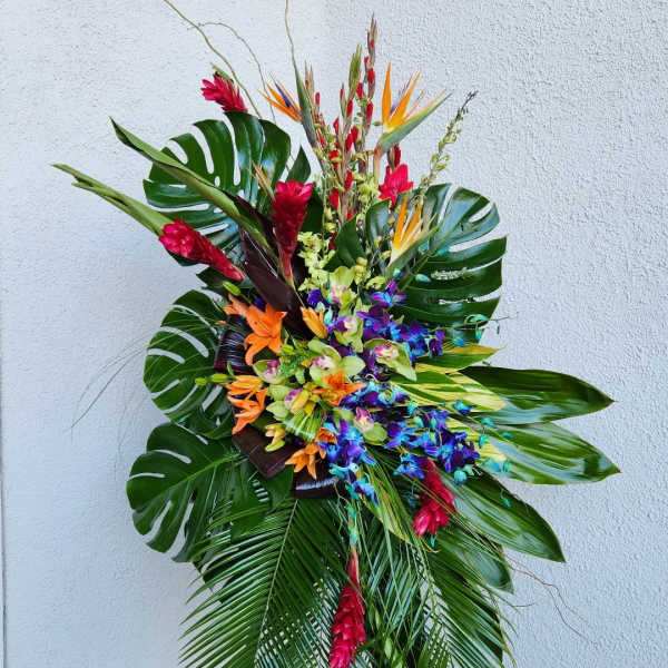 Tall tropical floral spray with bright orchids and red blooms on an easel