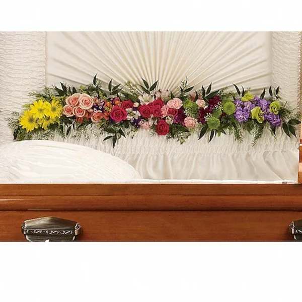 Colorful floral spray arranged across a white casket
