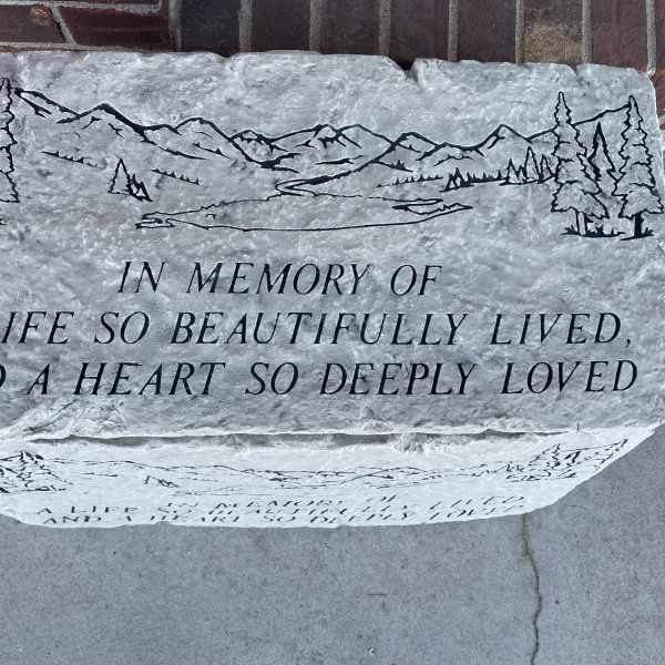 Engraved memorial stone with mountain and pine tree design