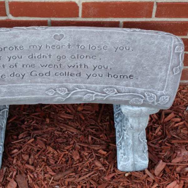 Gray memorial bench with an engraved sympathy message