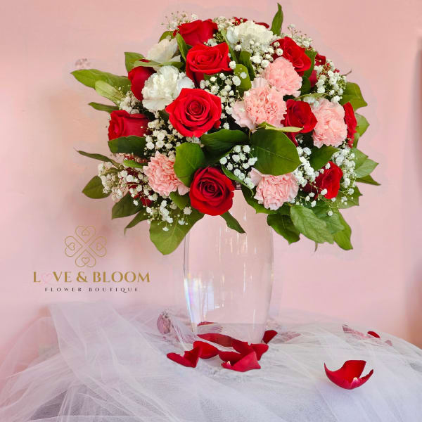 Red and pink rose bouquet in a clear vase with white filler flowers
