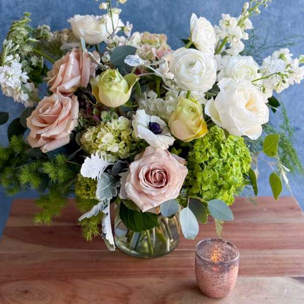 Mixed bouquet of pale roses and white blooms in a glass vase