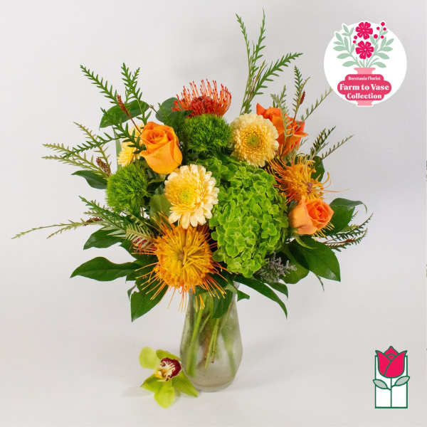 Orange roses and yellow blooms in a glass vase