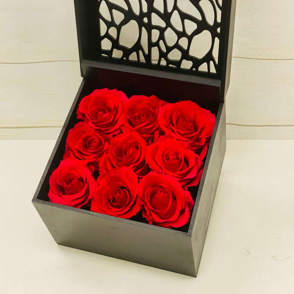 Square black gift box of nine red roses with an open decorative lid