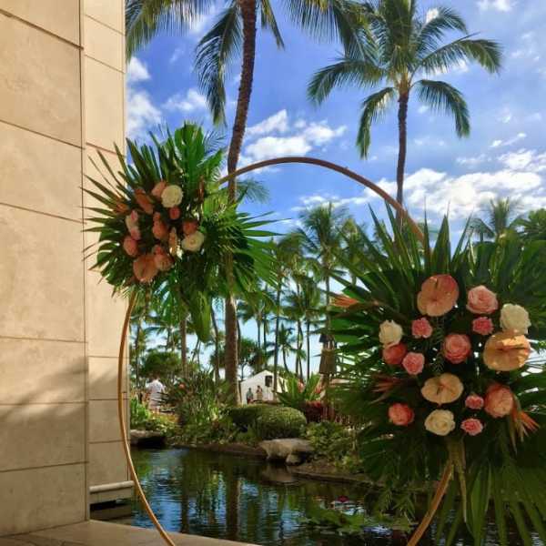 Two floral arrangements on a circular stand beside a tropical pool