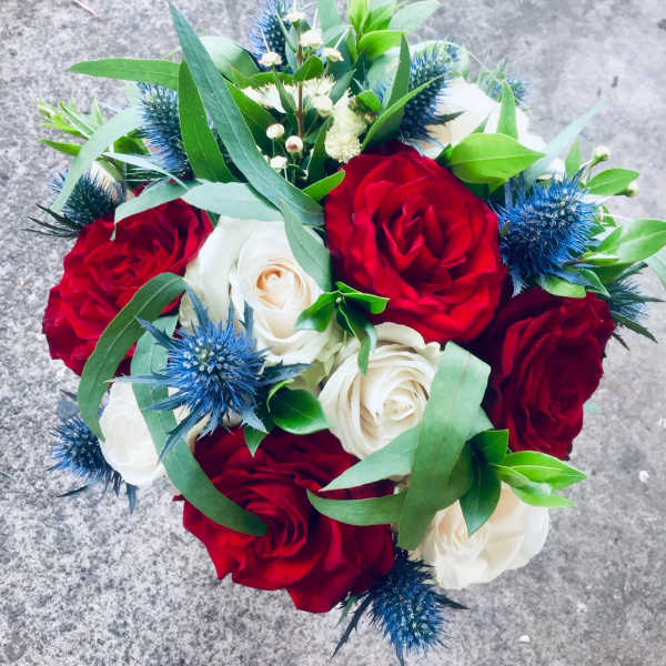 Bouquet of red and white roses with blue thistle accents