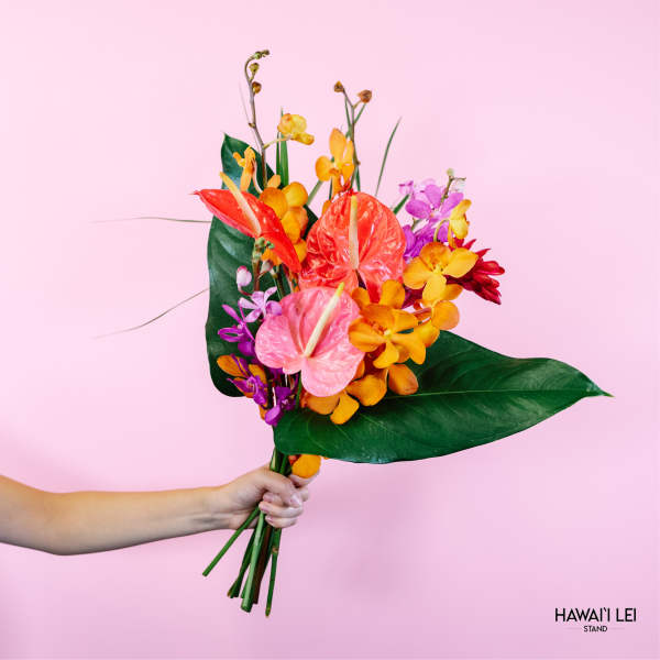 Handheld tropical bouquet with anthuriums and orchids on a pink background
