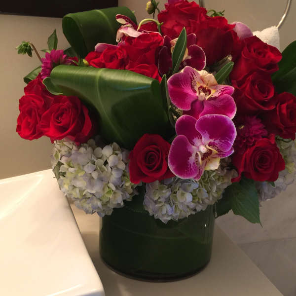 Red roses and purple orchids in a dark green vase