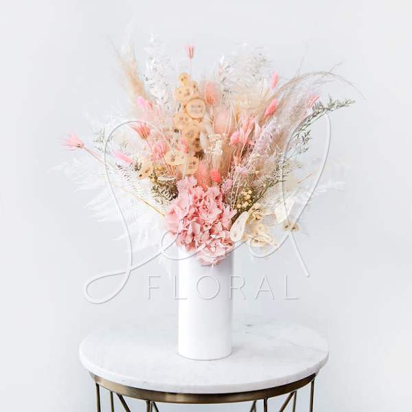Pink dried floral arrangement in a white vase