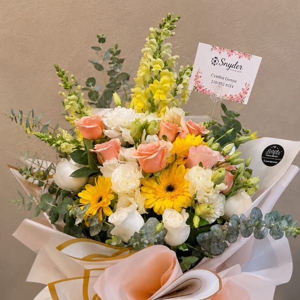Bouquet of peach and white roses with yellow flowers in a glass vase