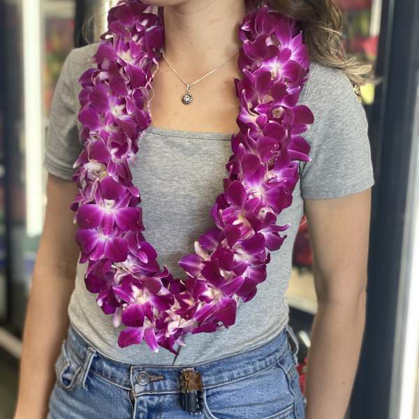 Woman wearing a purple orchid lei over a gray shirt