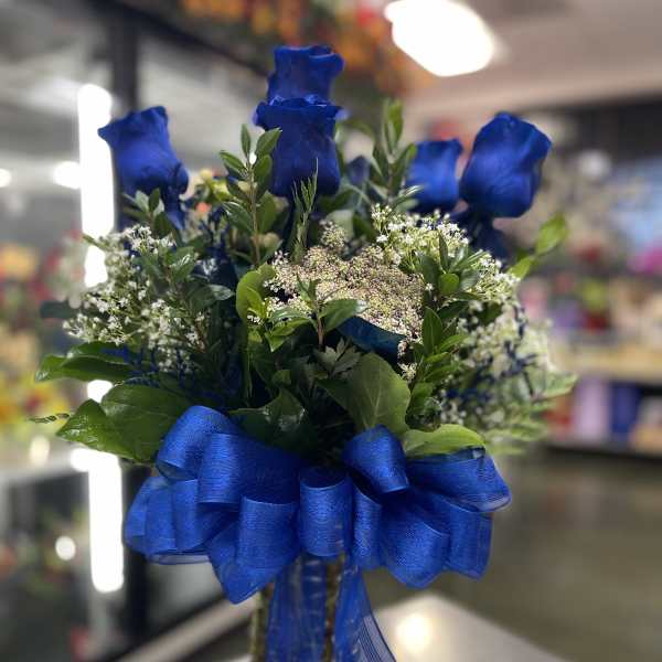 Blue roses in a glass vase with a large blue ribbon