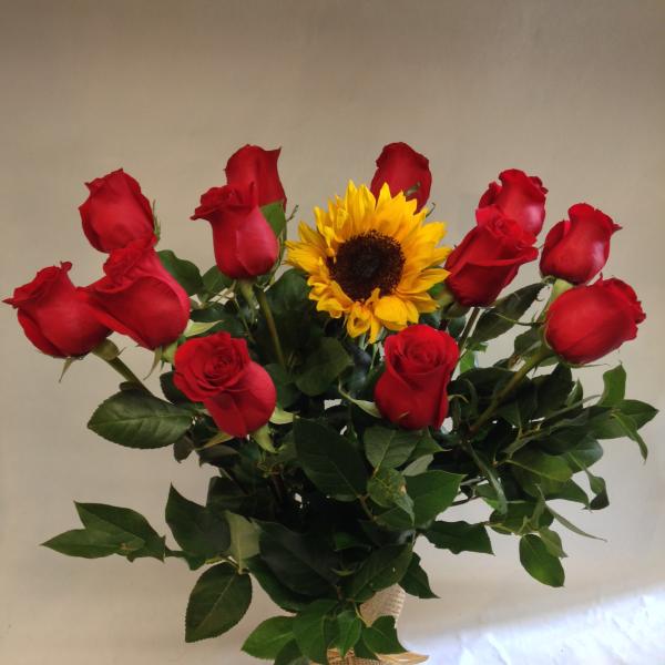 Bouquet of red roses and a sunflower in a burlap-wrapped vase