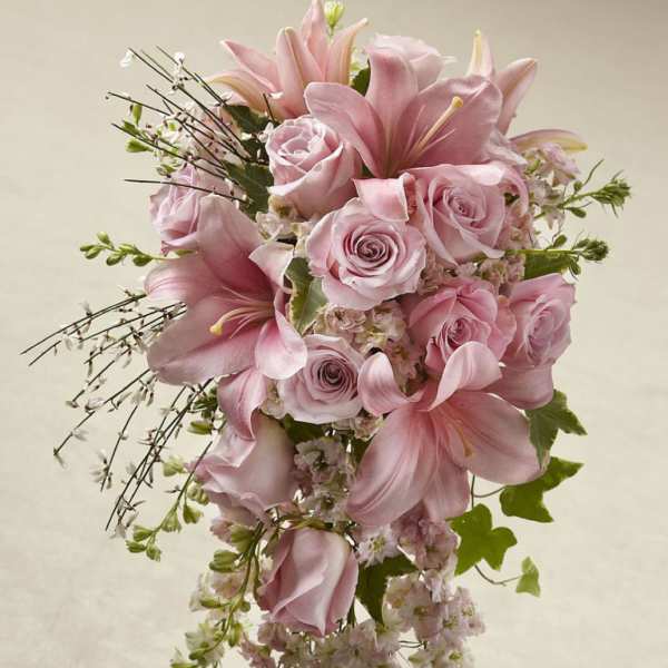 Pink roses and lilies in a cascading bouquet with trailing blossoms
