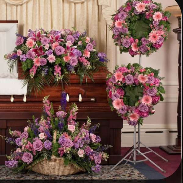 Casket surrounded by pink and purple funeral flower arrangements