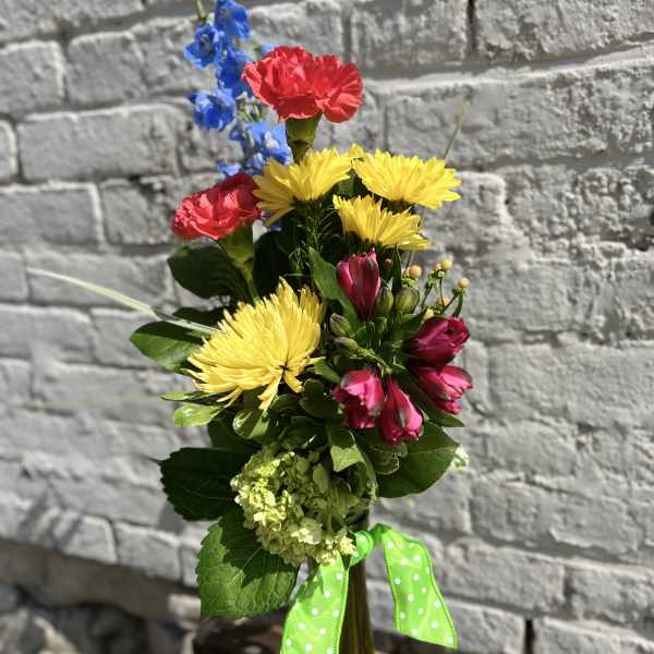 Colorful mixed bouquet in a tall glass vase with a green ribbon