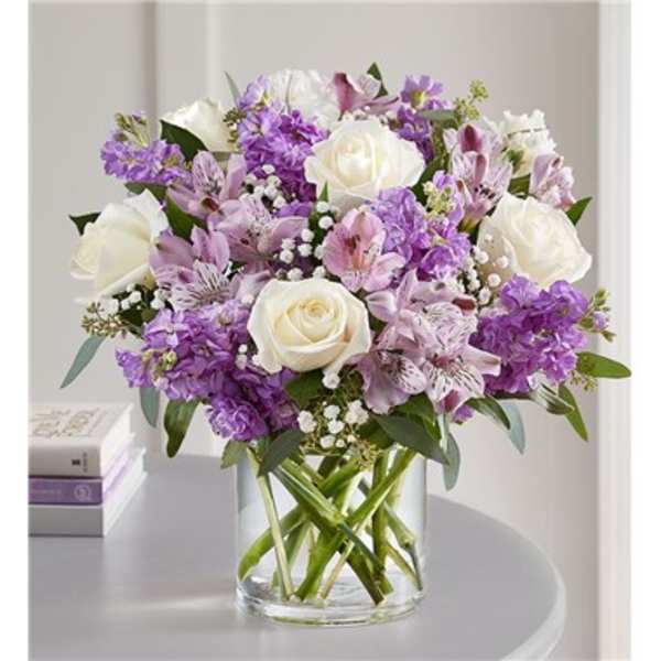 Bouquet of white roses and purple flowers in a clear glass vase