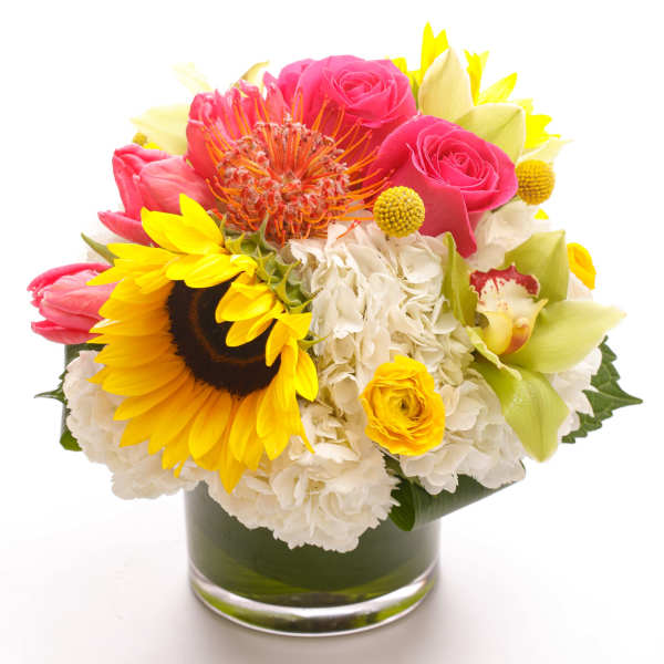 Bright mixed bouquet in a glass vase with sunflowers, pink roses, and white hydrangeas