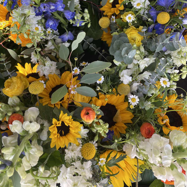 Mixed bouquet with sunflowers, blue delphinium, and white blooms