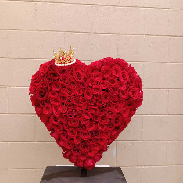 Heart-shaped arrangement of red roses with a small crown topper
