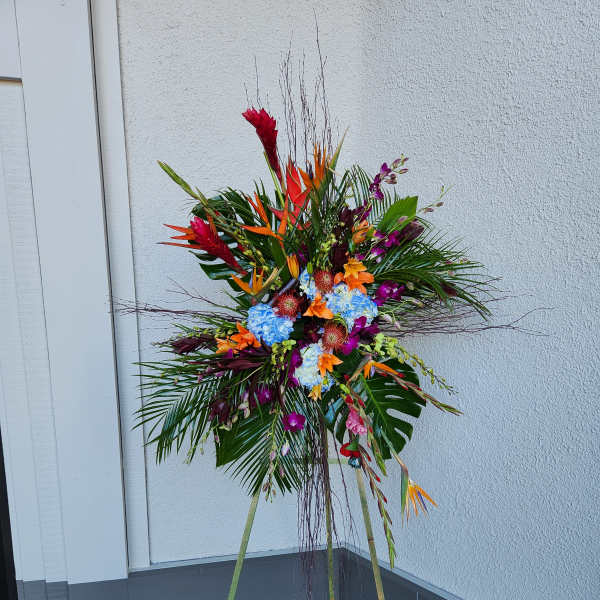 Tall tropical floral standing spray with bright mixed blooms on a tripod easel