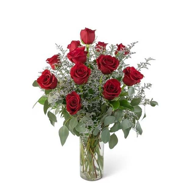 Red roses arranged in a clear glass vase with airy filler