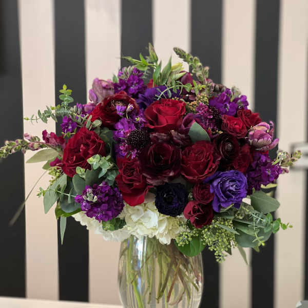 Bouquet of red, purple, and white flowers in a clear glass vase