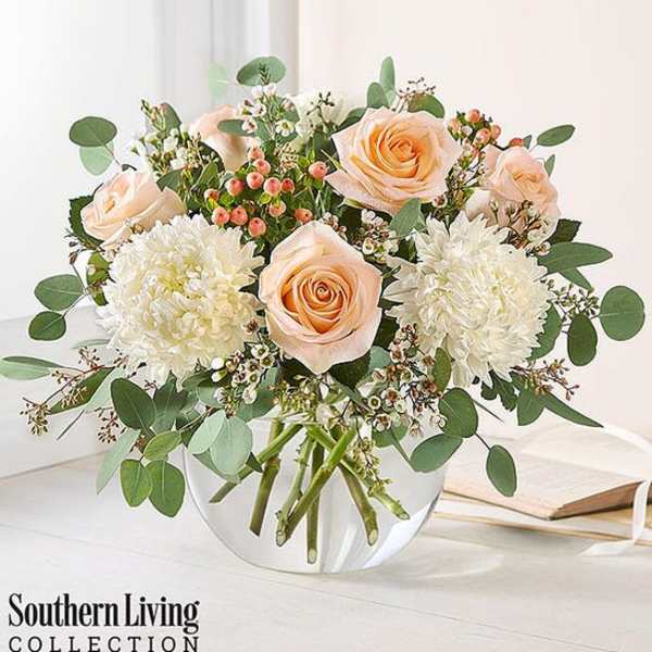 Peach roses and white mums in a clear glass vase