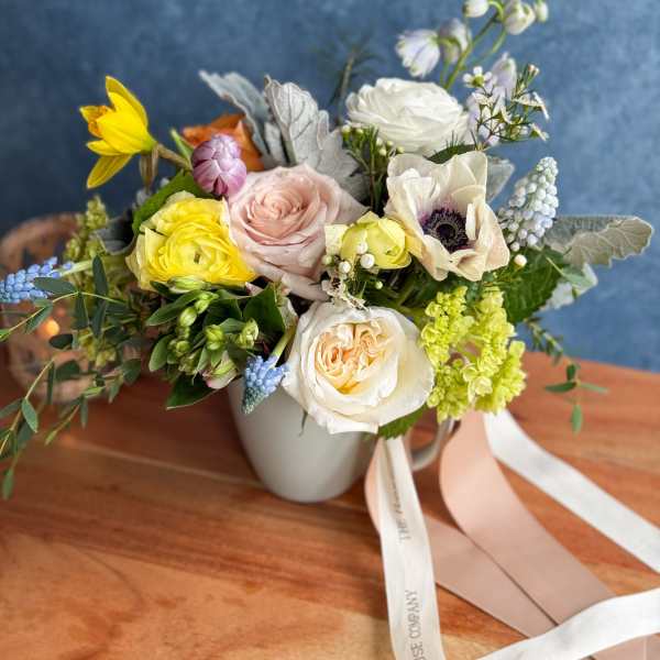 Mixed bouquet in a white mug-style vase with pastel roses and anemones