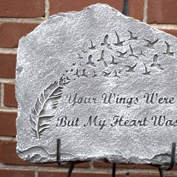 Engraved memorial stone with birds and a feather design