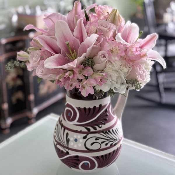 Pink lilies and roses arranged in a patterned vase