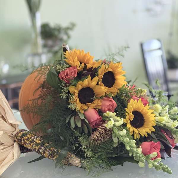 Bouquet with sunflowers and pink roses beside a pumpkin