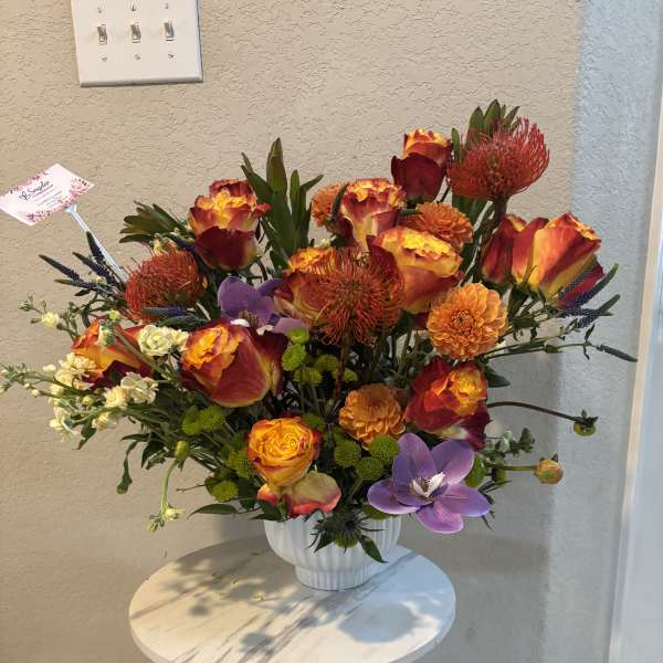 Bright mixed bouquet in a white vase with orange, red, and purple blooms