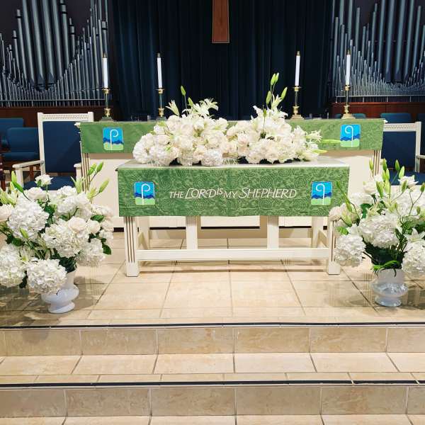 White floral altar arrangements in a church with green altar cloths