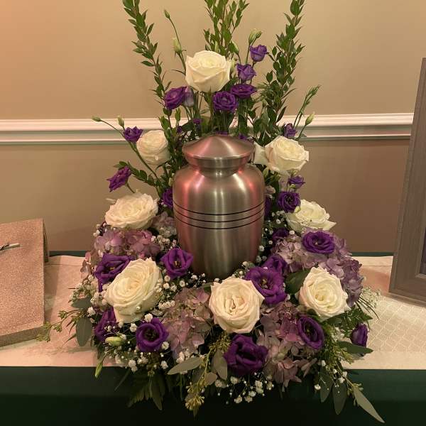 White and purple roses arranged around a silver urn